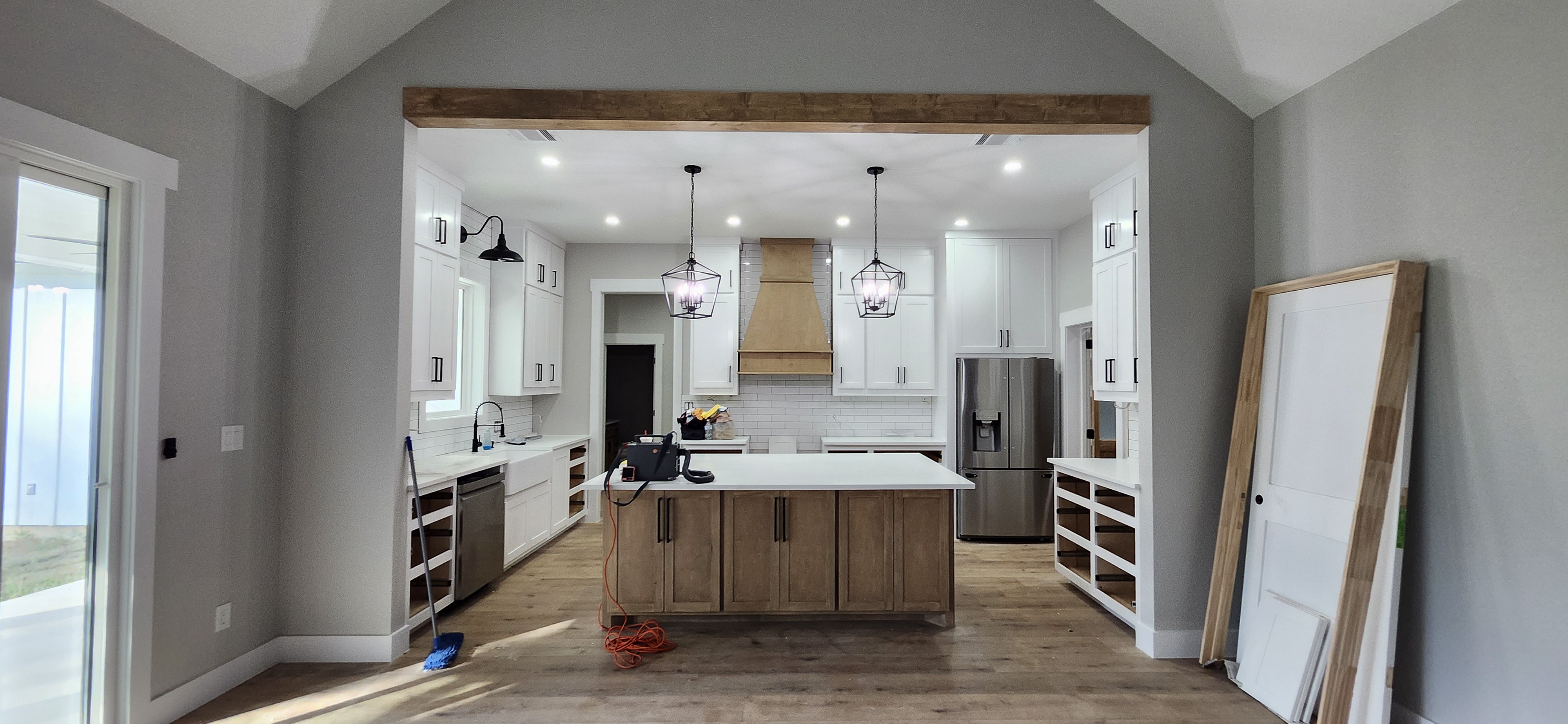 Custom farmhouse kitchen — white shaker cabinets, wood-tone island, exposed beam, Conroe TX