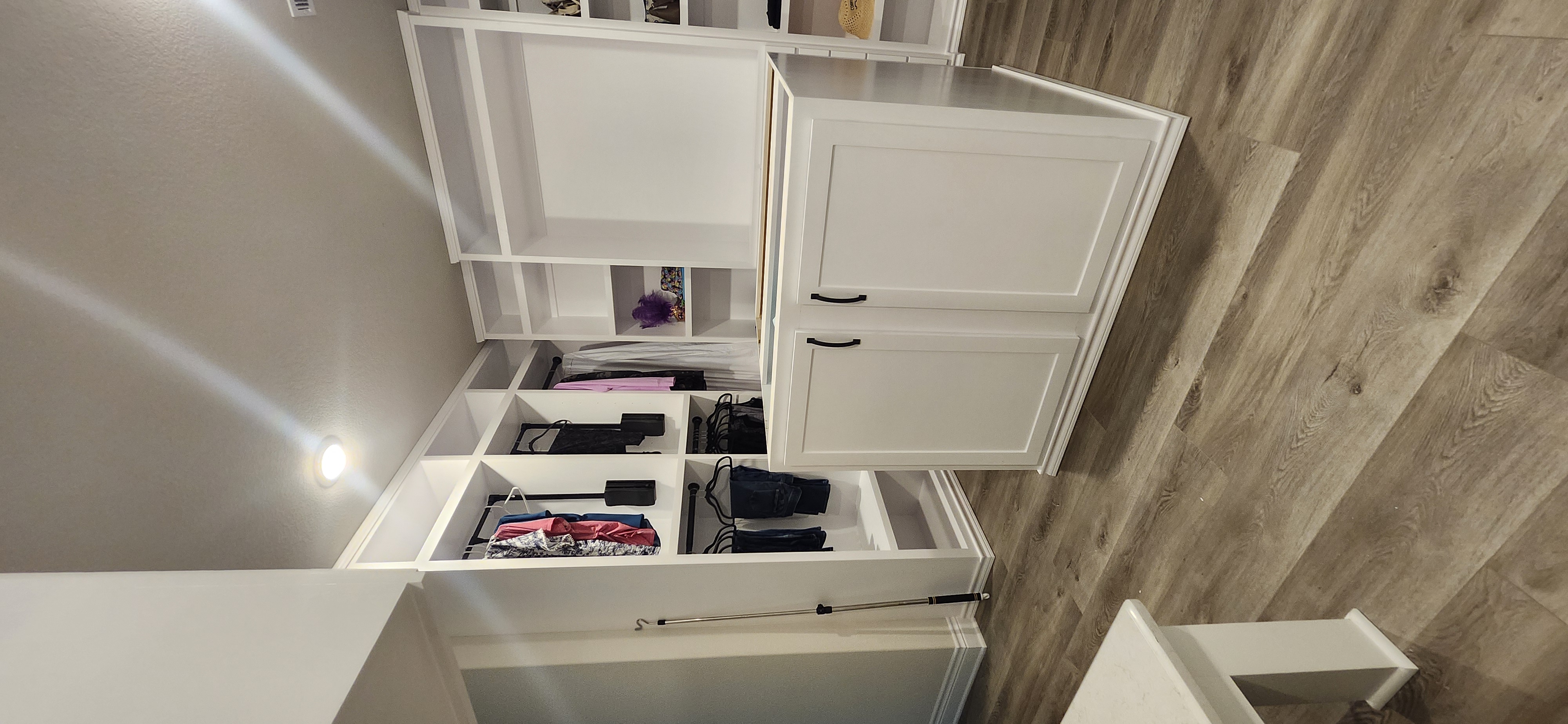 Custom walk-in closet with island, floor-to-ceiling white cabinetry, crown moulding