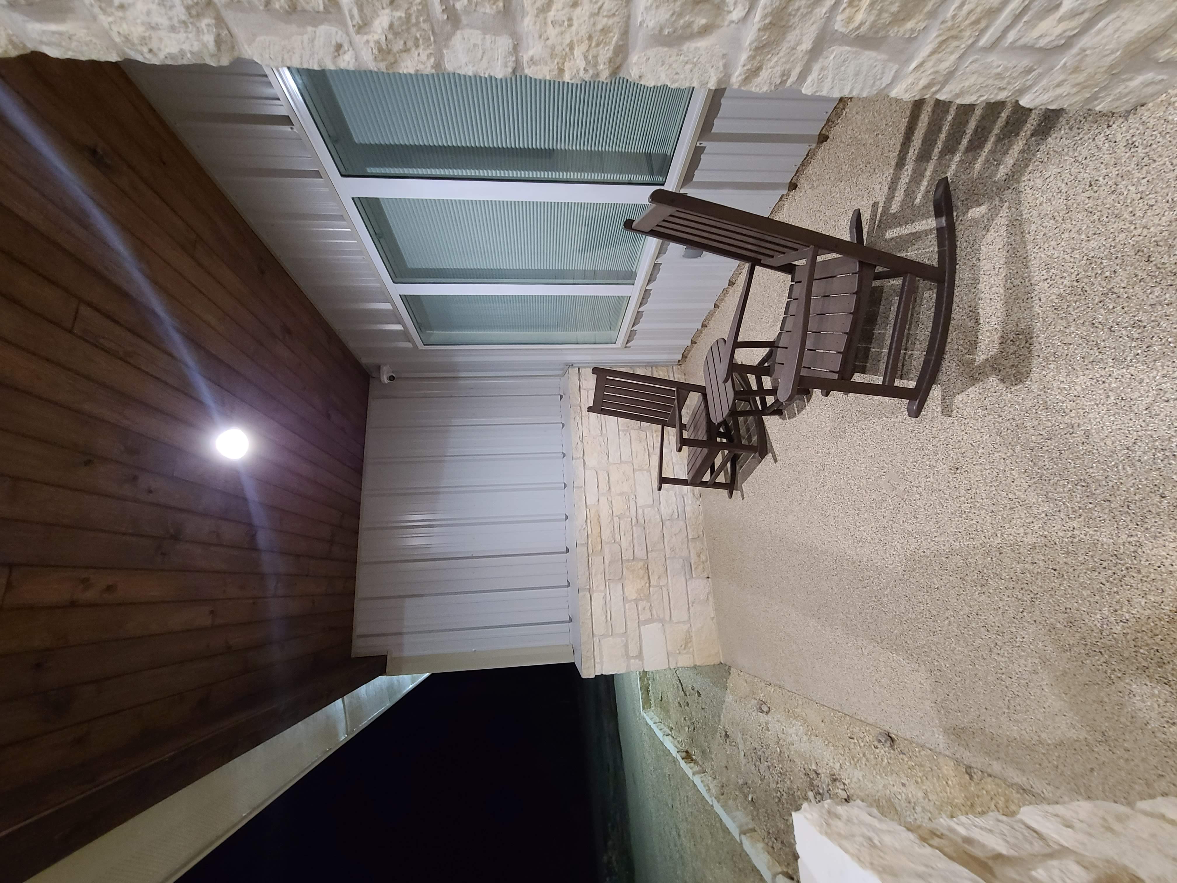 Covered porch rocking chairs stone columns wood ceiling night