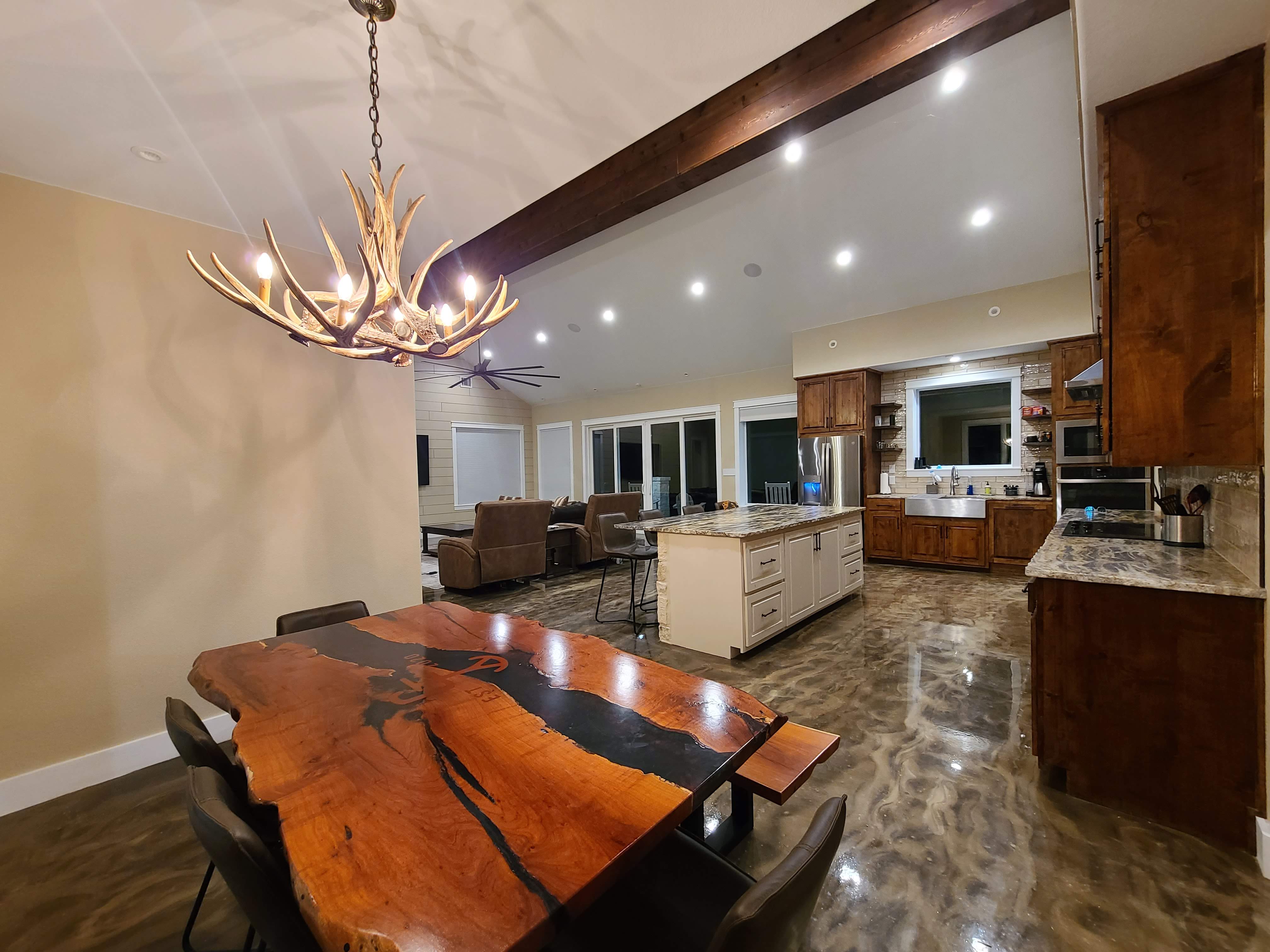 Live edge dining table antler chandelier open kitchen epoxy floor