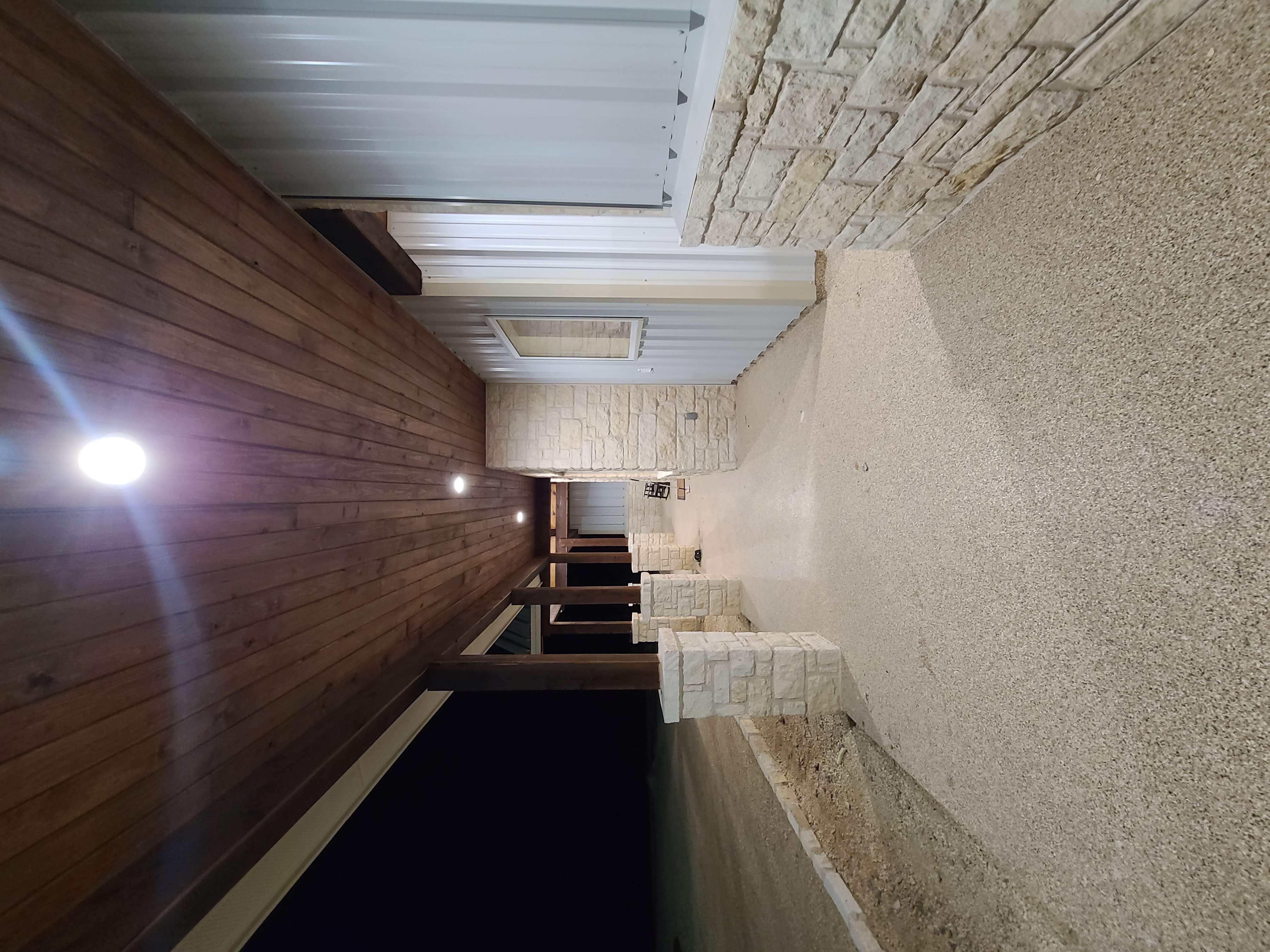 Long covered porch walkway stone pillars wood ceiling epoxy floor night