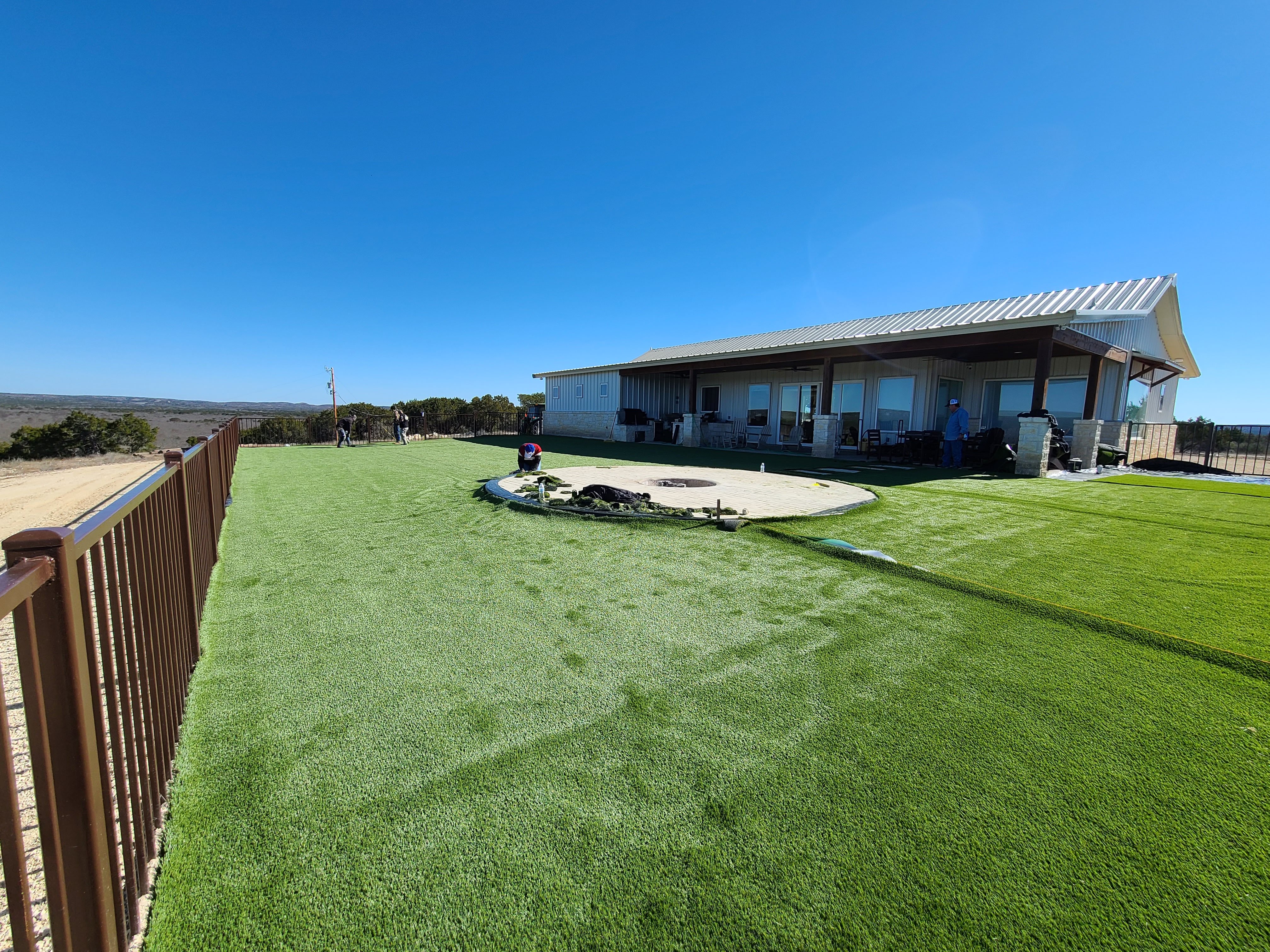 Custom ranch home artificial turf yard fire pit covered back porch Texas sky