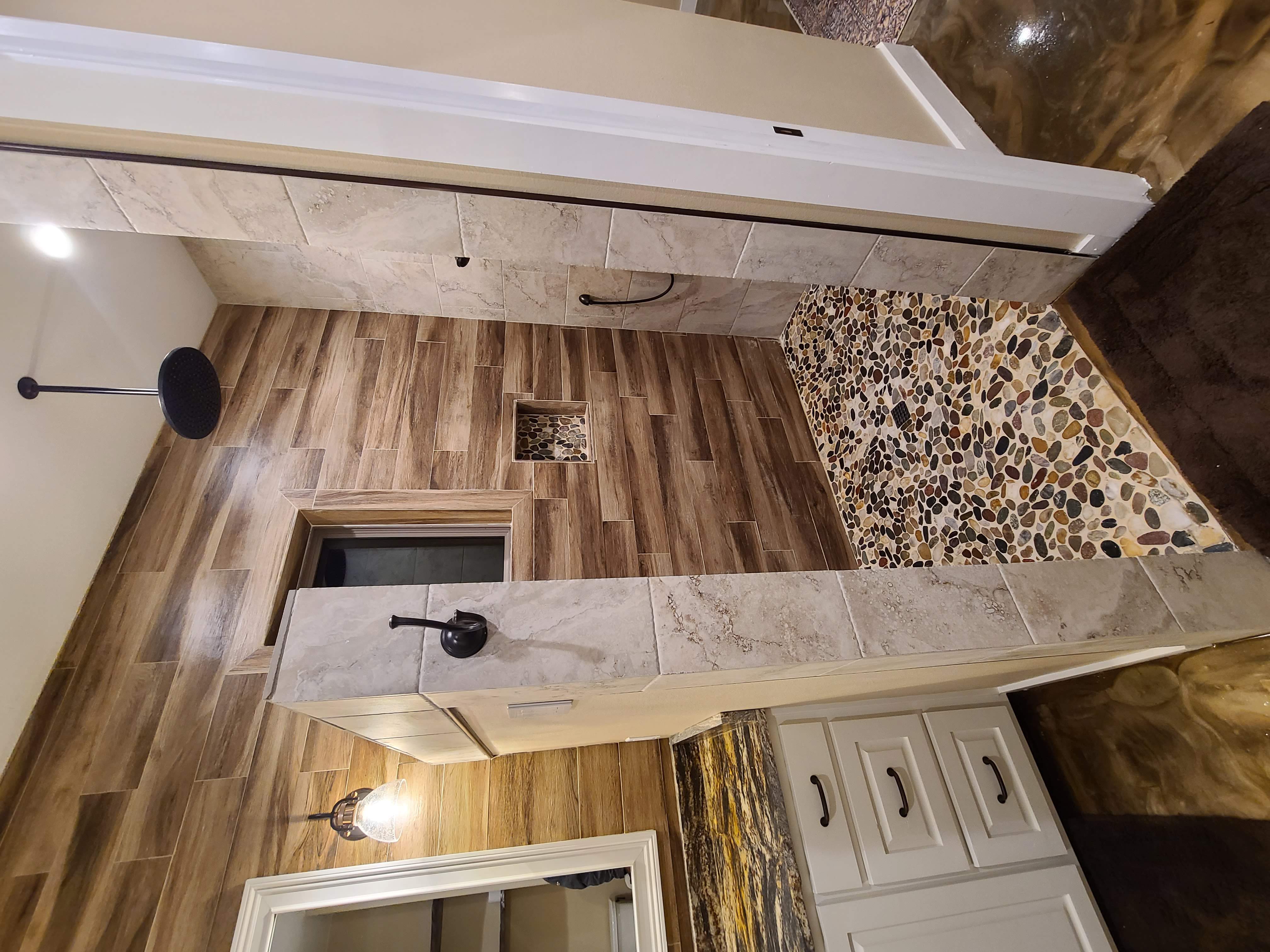 Walk-in shower pebble floor wood tile walls rain head niche